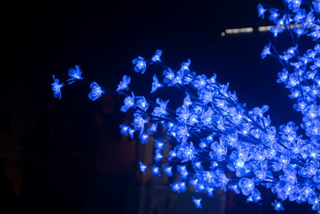 Christmas decoration with blue lights on blooming artificial branch on dark background. holiday conceptの写真素材