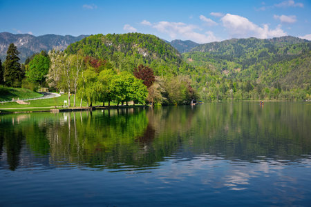Calm water reflecting surrounding trees and mountains in Lake Bled, Slovenia