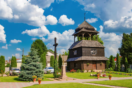Ascension Church wooden bell tower with its unique architecture and beautiful surroundings in Chortkiv, Ternopil region, Ukraine, creates a picturesque scene under a summer skyの写真素材