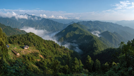 An expansive landscape showcases a series of verdant mountains under a bright blue sky. The scene is illuminated by sunlight, with soft white clouds adding depth. The image presents a natural environment, suitable for illustrating nature themes, travel, or environmental concepts for potential commercial usage.の素材