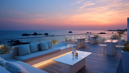 This image showcases a rooftop terrace with seating arrangements and cocktails, overlooking a vast ocean during a colorful sunset. The composition features a modern aesthetic with neutral tones, soft lighting, and a tranquil atmosphere. Suitable for diverse applications, including travel, lifestyle, and hospitality related projects.の素材