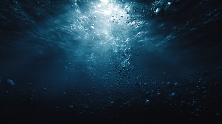 The image displays an underwater scene, featuring bubbles rising towards the surface. Sunlight streams penetrate the water creating beams. The color palette is dominated by blues and hints of light. The composition could be used in various commercial applications or to represent themes such as exploration.の素材