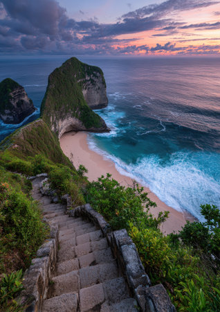 An aerial view presents a stunning coastal scene featuring a rugged cliff, sandy beach, and ocean waves. The image showcases vibrant colors from the setting sun, illuminating the sky and reflecting on the water. The composition highlights natural textures and offers visual appeal for various commercial applications.の素材
