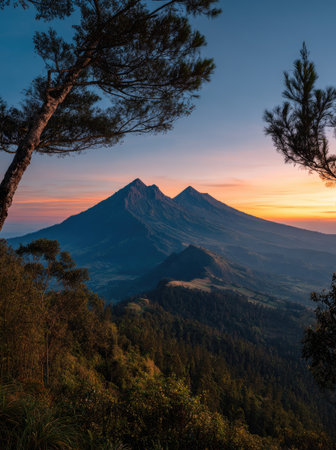 Dramatic landscape depicts mountain peaks against an early morning sky. The scene is dominated by layers of mountains and trees. The image showcases soft colors including blues, oranges, and greens. It has a high-angle shot, suggesting a vast environment. Suitable for travel, nature, or environmental themes.の素材