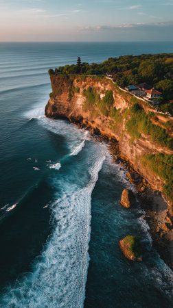 An aerial perspective captures a towering coastal cliff meeting the ocean. The image displays the interaction of water and land, showcasing foamy waves. The scene features natural lighting and a view of the sea's horizon. Suitable for commercial and editorial purposes.の素材