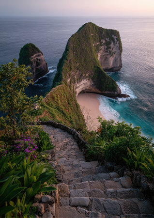 An aerial view presents a stone pathway descending towards a hidden beach. The scene features lush green vegetation, towering cliffs, and the rhythmic motion of turquoise waves. The composition utilizes natural lighting to highlight the textures of rock and sand, suitable for travel, tourism, and environmental projects.の素材