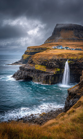 A picturesque coastal scene showcases a waterfall cascading into the ocean. The image features a rugged cliff face with shades of brown, green and yellow. The sea presents a cool turquoise hue, complementing the dark, moody sky. This type of imagery can be used for travel, nature, or environmental projects.の素材