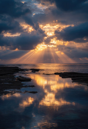 A striking scene features dramatic sun rays breaking through dark, layered clouds. The golden light illuminates the water, creating a stunning reflection of the sky above. This natural environment evokes a sense of awe and is suitable for various commercial and artistic projects.の素材