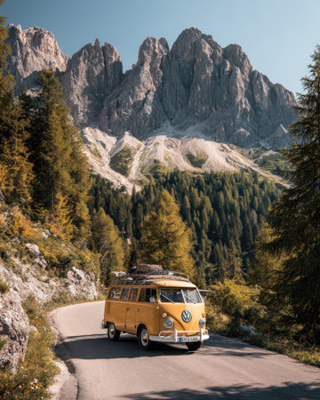 A yellow van traverses a winding road, the vehicle's design evoking a sense of adventure. Towering mountains and lush forest serve as a backdrop, creating a picturesque outdoor scene. The composition utilizes natural lighting, emphasizing the vibrant colors and textures suitable for travel or lifestyle content.の素材