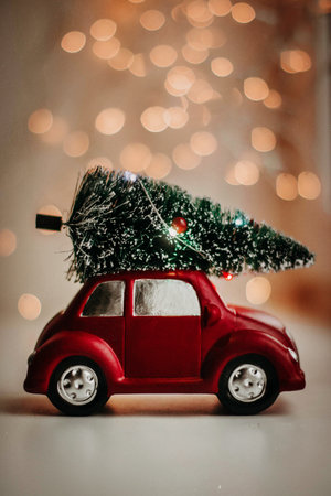 Red toy car with christmas tree on roof over bokeh backgroundの素材
