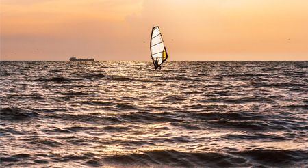 Windsurfing in the sea at sunset on the stormy cloudsの写真素材