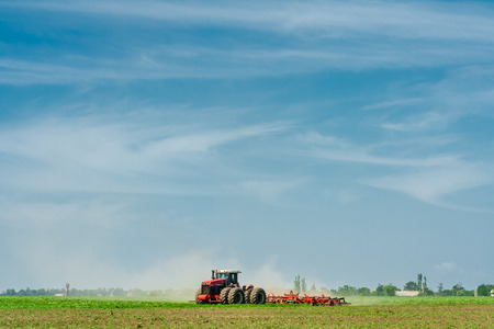 The tractor in the field on the background of blue sky