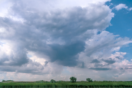 Picturesque thunderclouds over the  bank of the river