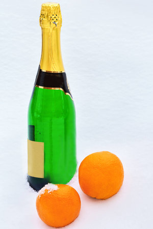 Bottle of champagne and two oranges in the snowの写真素材