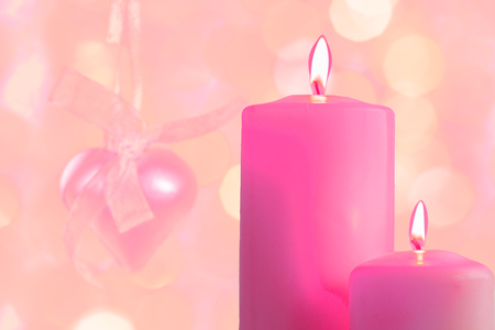 Pink burning candles on a blurred festive background, close-upの写真素材