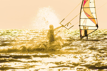 Kitesurfing and windsurfing in the sea at sunset in the backlightの写真素材