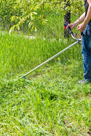 Garden work, mowing grass in the garden on a summer day