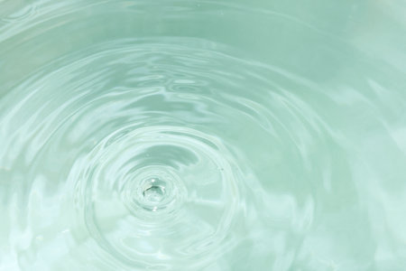 Water drop falling into water with ripples and ripples. Abstract backgroundの写真素材