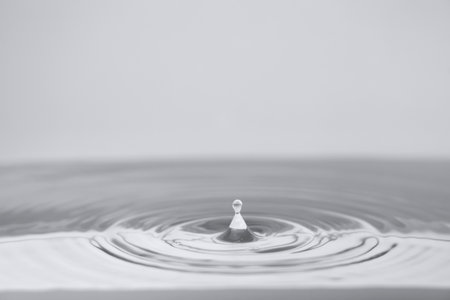 Water drop falling into water with ripples and ripples on itの写真素材