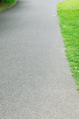 Asphalt road in the park with green grass in the background.