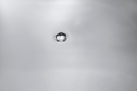 Close up of a water drop in a white bathroom sink with copy spaceの写真素材