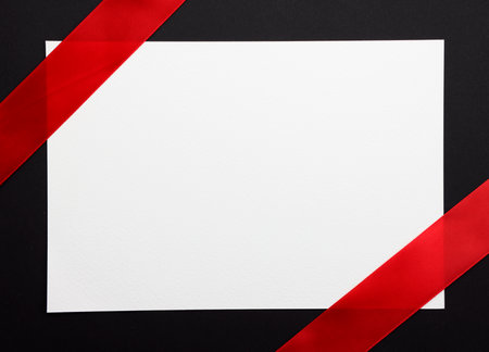 Blank card with red ribbon on black background. Top view.の写真素材