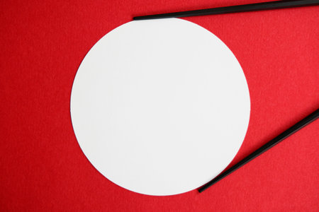 White circle with black chopsticks on a red background. Top viewの写真素材