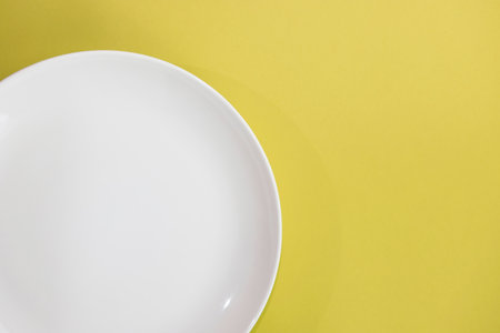 Empty white plate on yellow background. Top view. Copy space.の写真素材