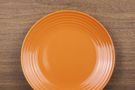 Empty orange plate on wooden background. Top view. Copy space.の写真素材