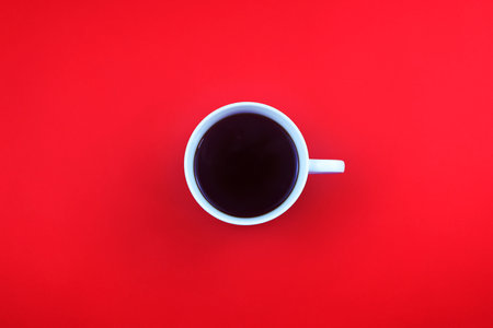 Top view of a cup of coffee on a red background with copy spaceの写真素材