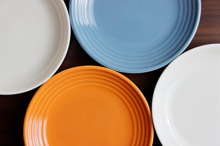 Colorful ceramic plates on wooden table. Top view with copy space