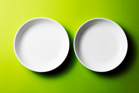 Empty white plates on a green background. Top view. Copy space.の写真素材