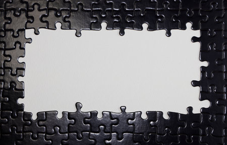 Close up of black puzzle pieces with white blank space for text.の写真素材