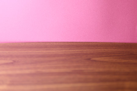 Wooden table top on pink wall background. Place for text.
