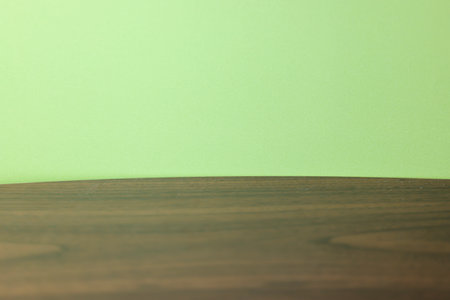Wooden table in front of green wall background with copy space.の写真素材