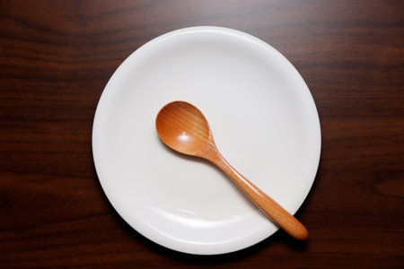 Wooden spoon on a white plate on a brown wooden table.の写真素材