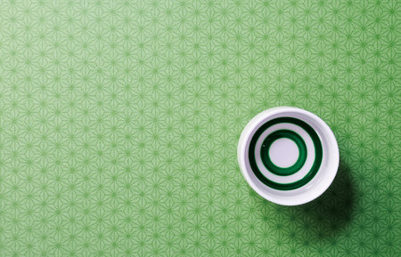 Top view of a sake cup on a green background with a Japanese pattern