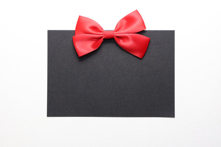 close up of a black card with a red bow on white background