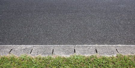 Asphalt road surface with grass at the side.