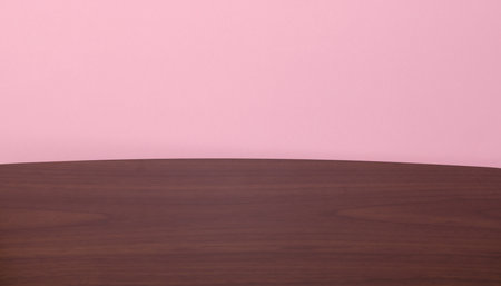 Wooden table top on pink background.