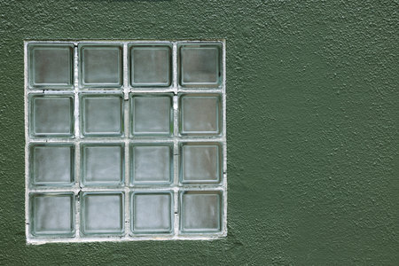 A close up of a plastic window on a green wall with copy space.