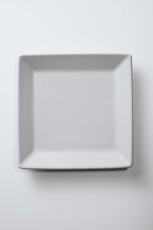 Empty white plate on a white background. Top view. Copy space.
