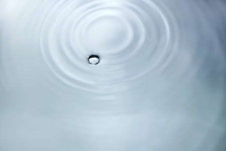 Drop of water on the surface of the rippled water.の写真素材