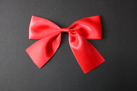 Red bow isolated on black background. Top view, flat lay.