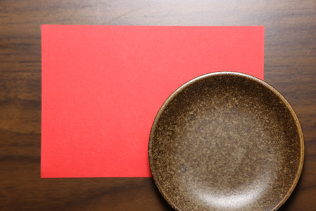 Empty plate and red paper on wood table background with copy space.の写真素材