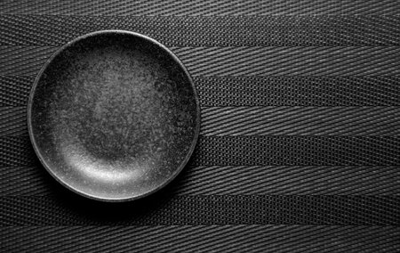 Empty plate on black textured background. Top view. Toned.の写真素材