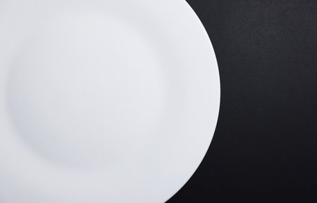 Empty white plate on black background. Top view. Flat lay.の写真素材