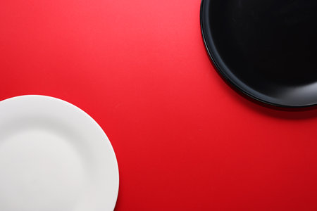 Empty black and white plate on red background. View from above.の写真素材