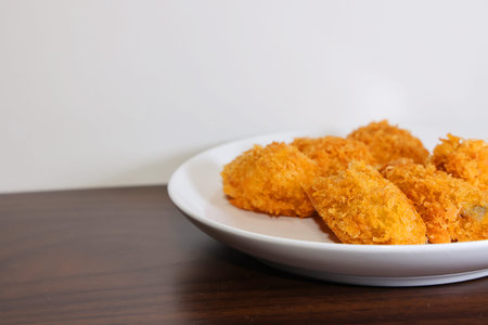 Fried oyster in white plate on wooden table.