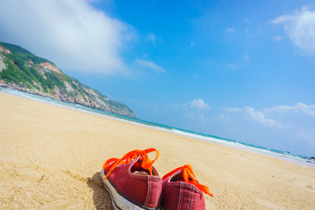 Orange shoes sit on a sandy beachの写真素材